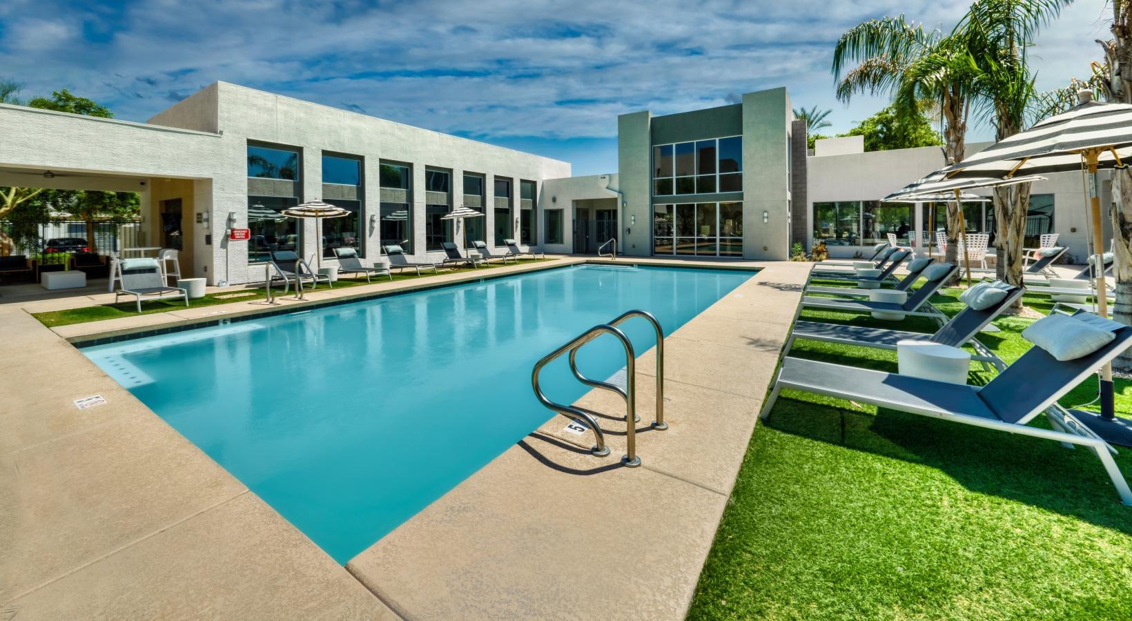 Relax and unwind poolside a swimming pool with lounge chairs around it